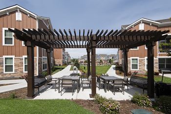 a patio with tables and chairs under a wooden pergola  at Watermark on Twenty Mile, Parker, Colorado